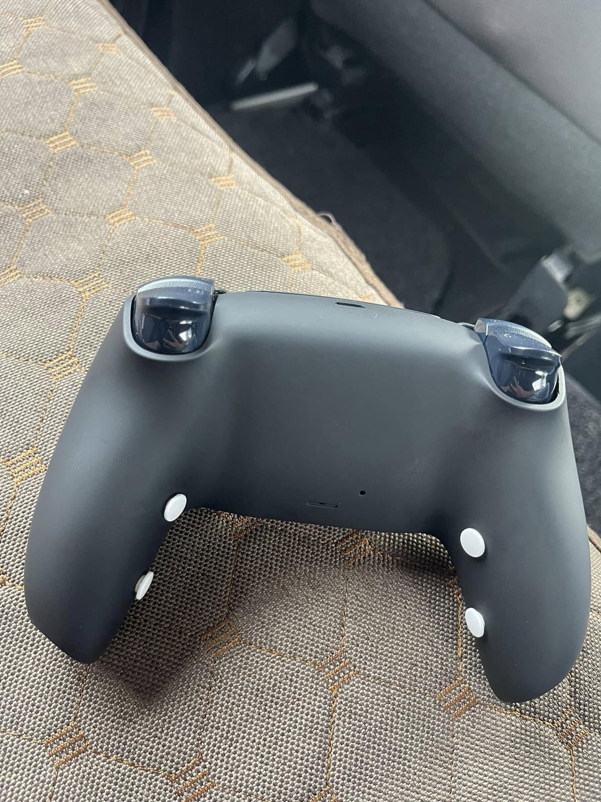 Rear view of a black HYPR DualSense controller with four white buttons